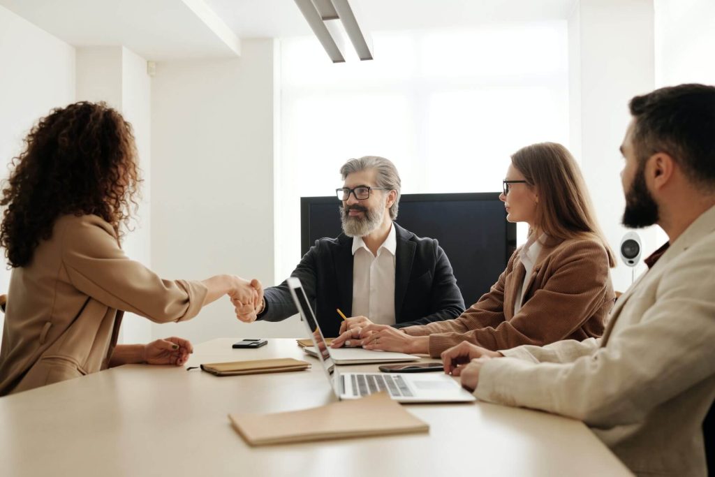 Man and woman shake hands with other two people