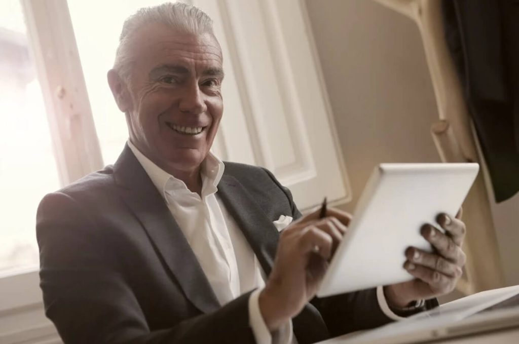 smiling old man holding a tablet become a business investors